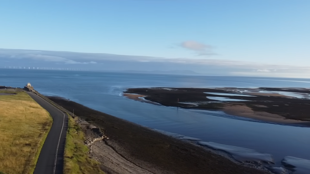 the road on the shore near the dark blue sea, the island near the land