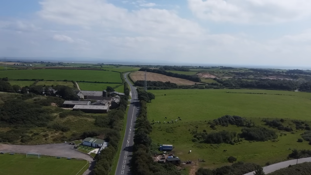 an aerial view of the countryside with fields and houses near the road